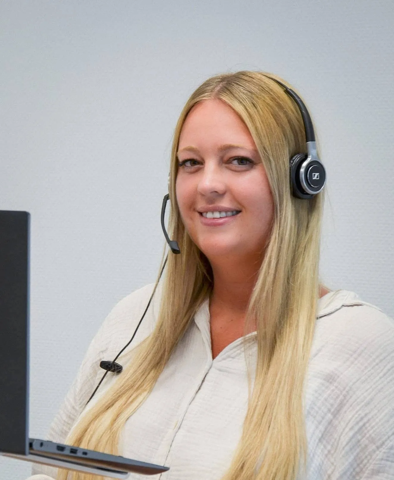 Eine freundliche Frau mit Headset arbeitet mit einem Laptop